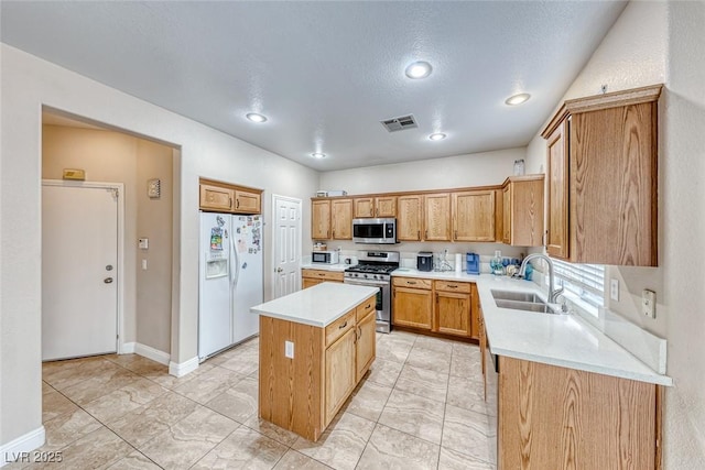 kitchen featuring a center island, stainless steel appliances, light countertops, visible vents, and a sink