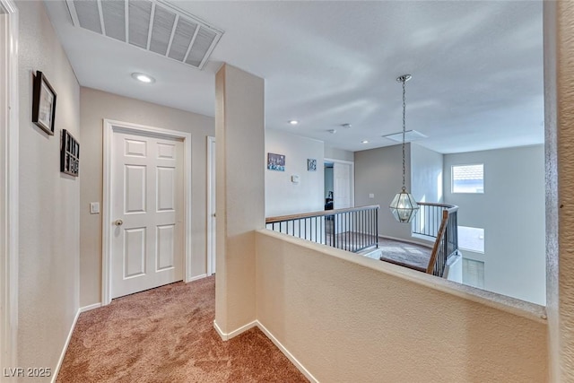 corridor with visible vents, carpet, an upstairs landing, and baseboards