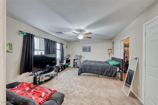 bedroom featuring a ceiling fan, carpet flooring, visible vents, and a textured ceiling