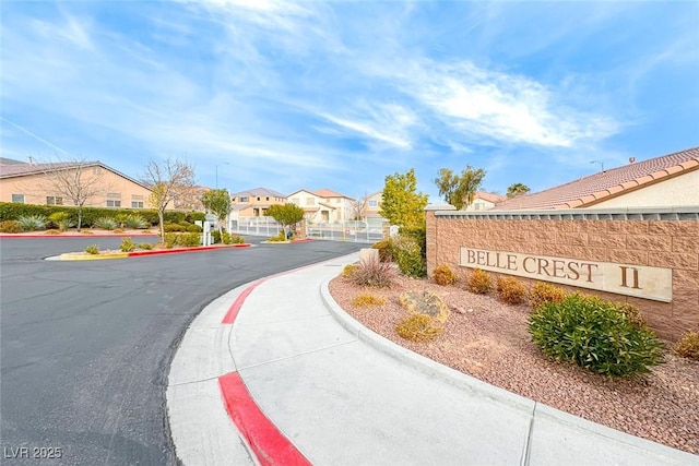 view of road featuring street lighting, sidewalks, a gated entry, a residential view, and curbs