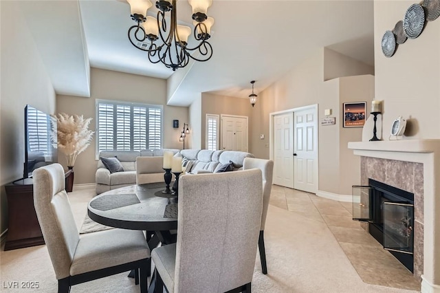 dining area featuring baseboards, a fireplace, high vaulted ceiling, a notable chandelier, and light tile patterned flooring