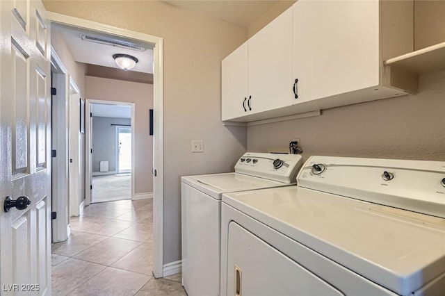 washroom with light tile patterned floors, cabinet space, visible vents, washing machine and dryer, and baseboards