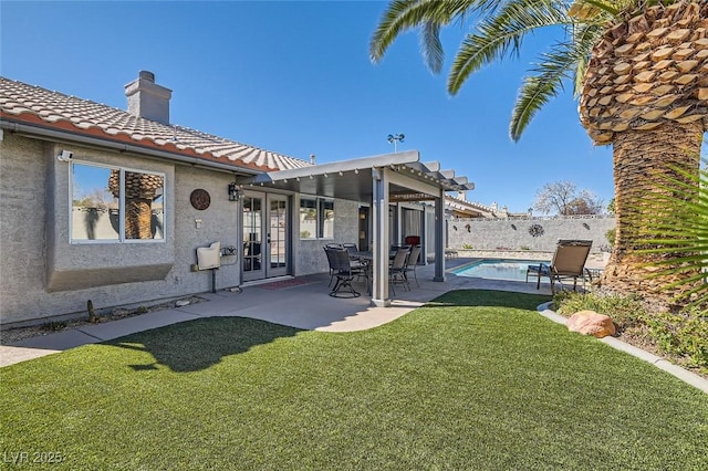 rear view of property with a patio, a fenced backyard, a chimney, french doors, and stucco siding