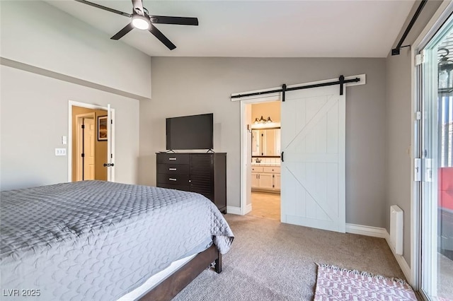 bedroom featuring lofted ceiling, light colored carpet, a barn door, connected bathroom, and baseboards