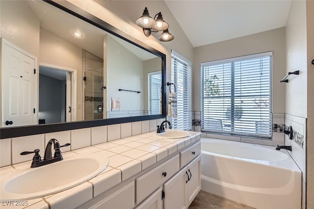 full bath with vaulted ceiling, a sink, a garden tub, and a shower stall