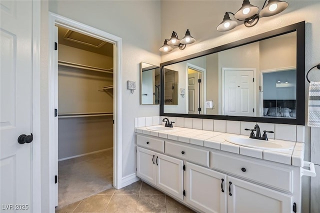 full bath featuring tile patterned floors, a sink, a spacious closet, and double vanity