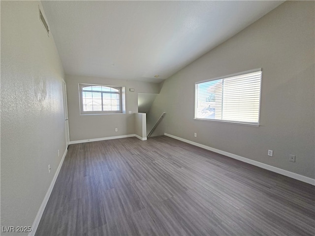 spare room with lofted ceiling, dark wood-style flooring, and baseboards