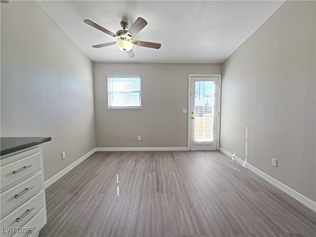 empty room with a textured ceiling, baseboards, and wood finished floors