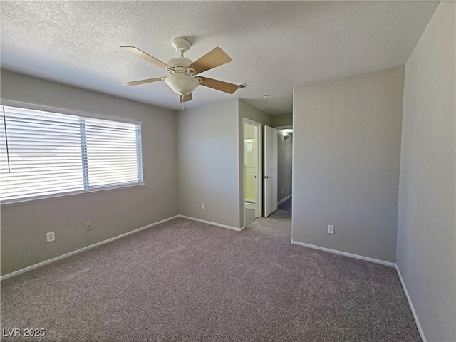 carpeted empty room with a textured ceiling, visible vents, a ceiling fan, and baseboards