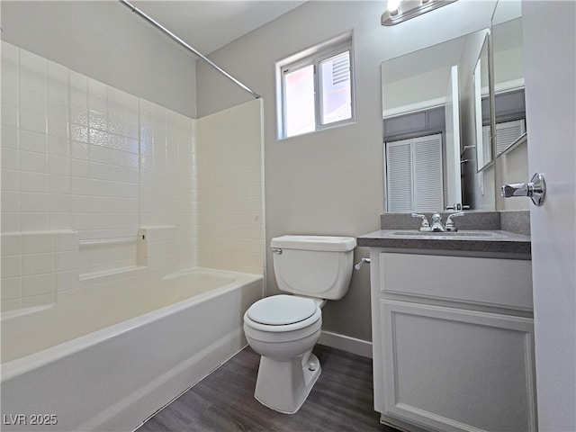 full bath featuring toilet, vanity, shower / tub combination, wood finished floors, and baseboards