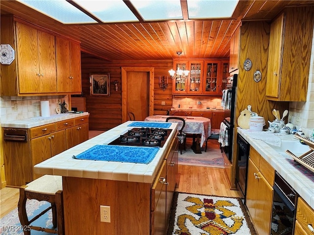 kitchen featuring light wood finished floors, a center island, tile counters, and brown cabinets
