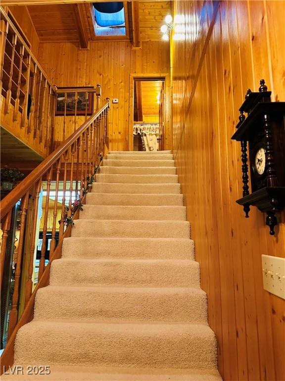 stairway featuring wooden walls and beam ceiling