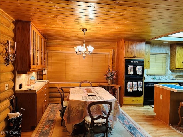kitchen with light wood finished floors, wood ceiling, an inviting chandelier, light countertops, and black appliances
