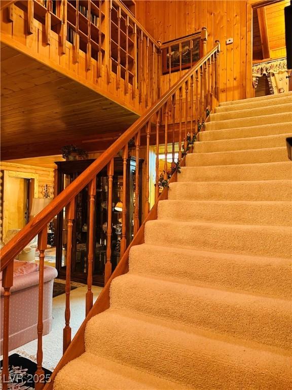 stairway featuring wooden ceiling, carpet flooring, and wooden walls