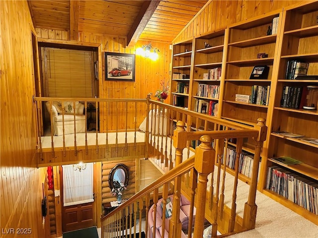 staircase with carpet floors, wood ceiling, wooden walls, and lofted ceiling with beams