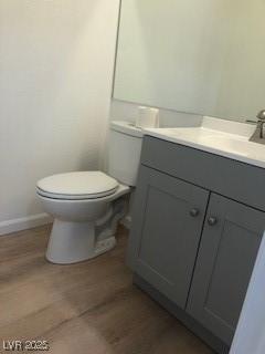 bathroom featuring baseboards, vanity, toilet, and wood finished floors