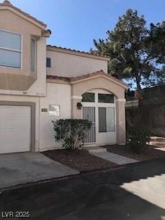 doorway to property featuring driveway, a garage, and stucco siding