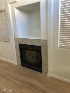 room details with baseboards, wood finished floors, and a tile fireplace