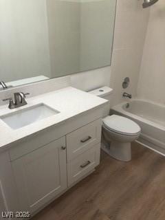 bathroom featuring vanity, bathing tub / shower combination, wood finished floors, and toilet