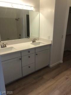 full bath with double vanity, wood finished floors, and a sink