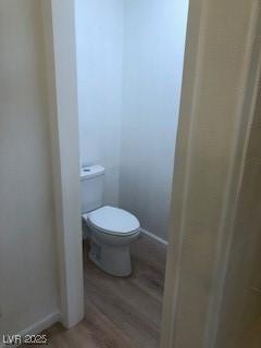 bathroom with toilet, baseboards, and wood finished floors