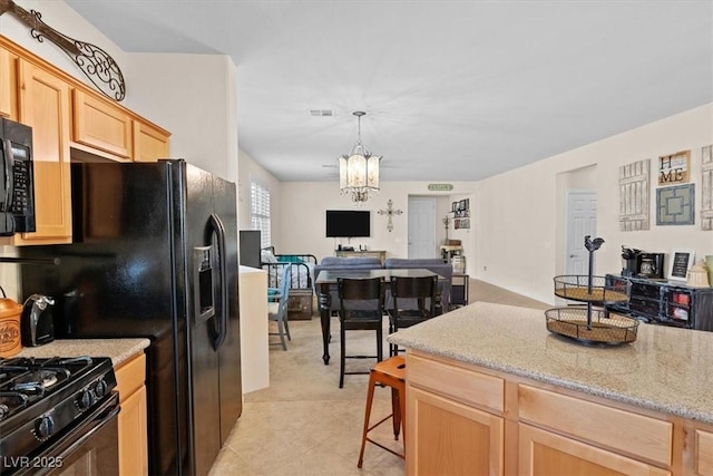 kitchen with a notable chandelier, open floor plan, light brown cabinets, black range with gas cooktop, and light stone countertops