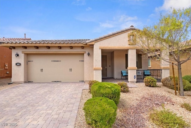 view of front of property featuring decorative driveway, an attached garage, and stucco siding