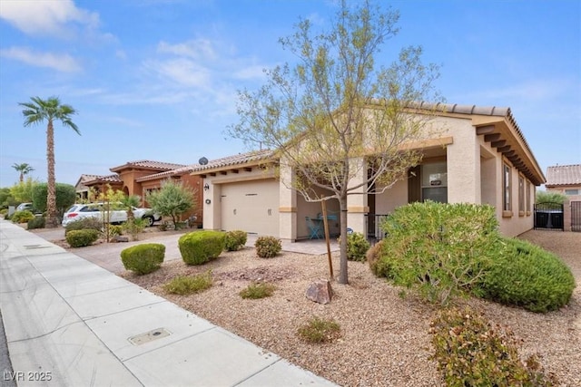 view of front of property with driveway, a tile roof, a garage, and stucco siding