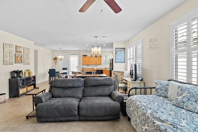 living room featuring ceiling fan with notable chandelier, visible vents, and light tile patterned floors