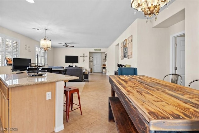 dining space with light tile patterned floors and ceiling fan with notable chandelier