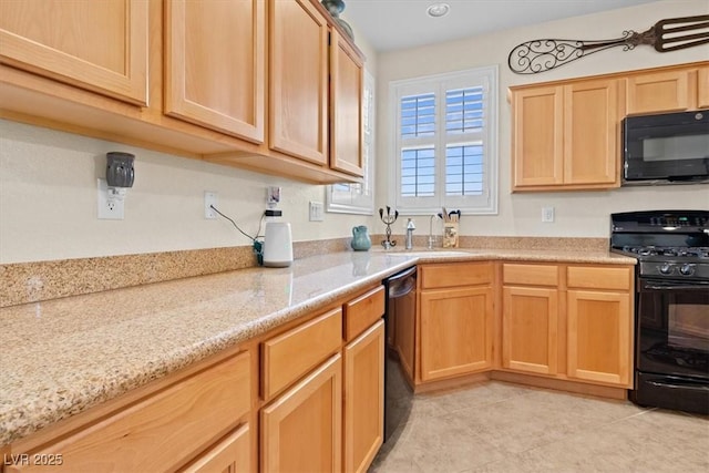 kitchen with black appliances, light brown cabinetry, a sink, and light stone counters