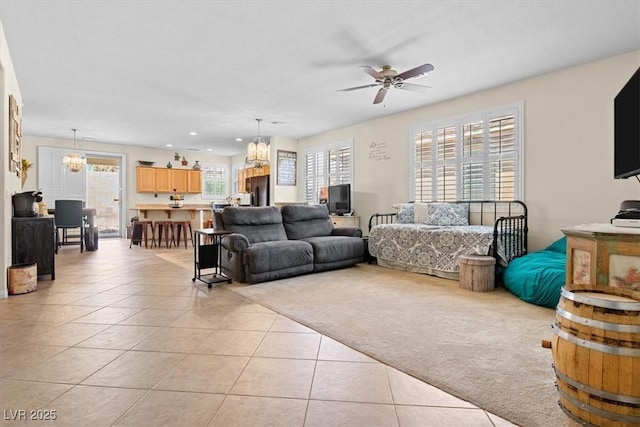 living room featuring light tile patterned floors, recessed lighting, ceiling fan with notable chandelier, and light colored carpet