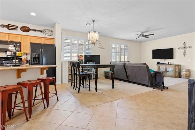 interior space with light tile patterned floors, visible vents, and ceiling fan with notable chandelier