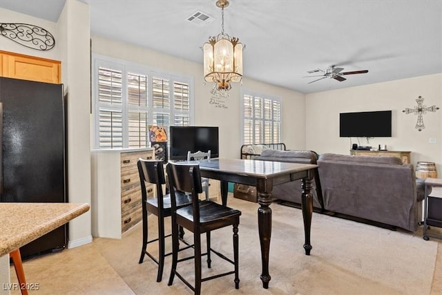 dining area with ceiling fan with notable chandelier and visible vents