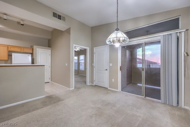 unfurnished dining area featuring light colored carpet, a notable chandelier, visible vents, and baseboards