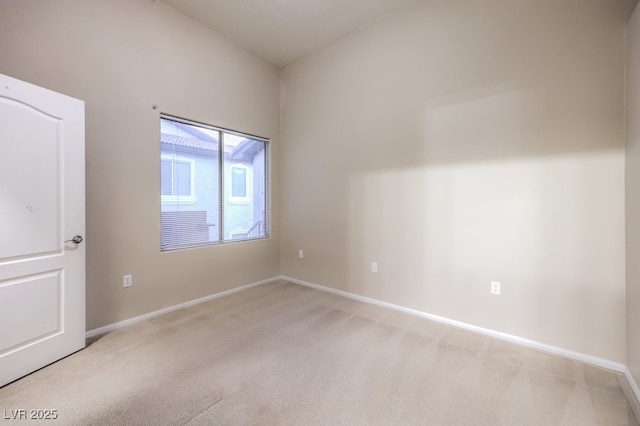 unfurnished room featuring light carpet and baseboards