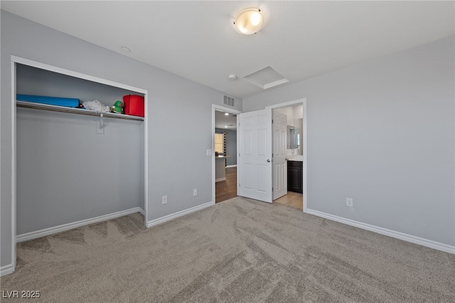 unfurnished bedroom with carpet flooring, visible vents, baseboards, a closet, and attic access