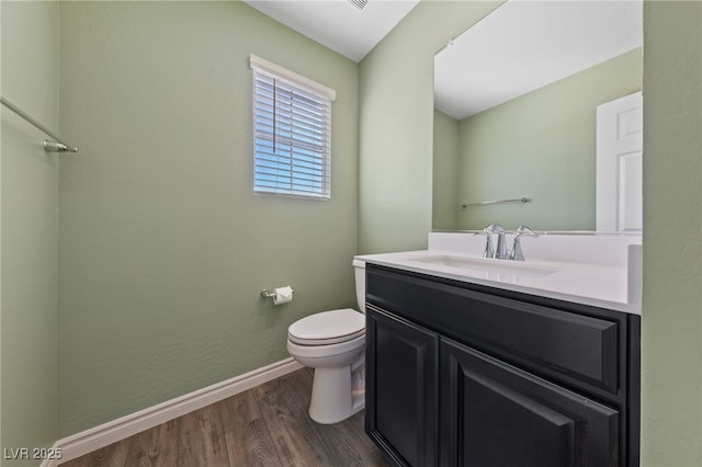 bathroom with toilet, baseboards, wood finished floors, and vanity