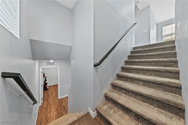 stairway with wood finished floors, visible vents, and baseboards