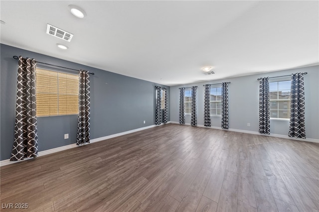 spare room featuring visible vents, baseboards, and wood finished floors