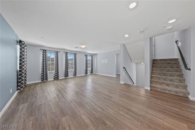 unfurnished living room with stairway, baseboards, and wood finished floors