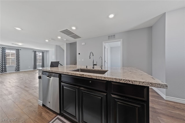 kitchen featuring dark cabinets, a sink, visible vents, open floor plan, and dishwasher