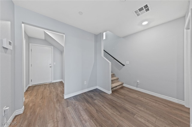 interior space featuring wood finished floors, visible vents, baseboards, and stairs