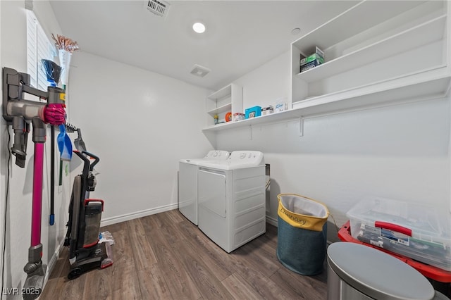 laundry room with visible vents, washing machine and dryer, wood finished floors, laundry area, and baseboards