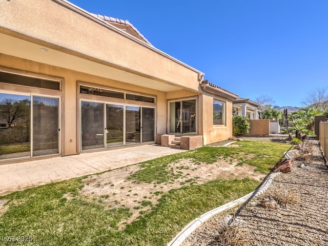 rear view of property with a patio area, fence, and stucco siding