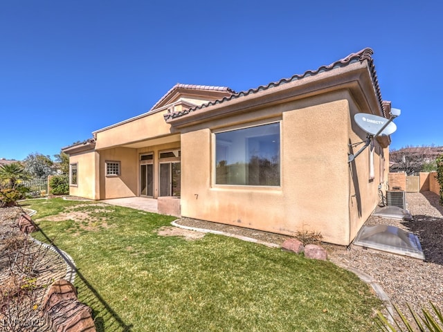 back of house featuring stucco siding, fence, and a lawn