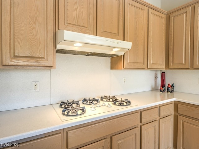 kitchen with light brown cabinetry, under cabinet range hood, light countertops, and white gas cooktop