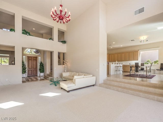 carpeted living room featuring a towering ceiling, plenty of natural light, visible vents, and a chandelier