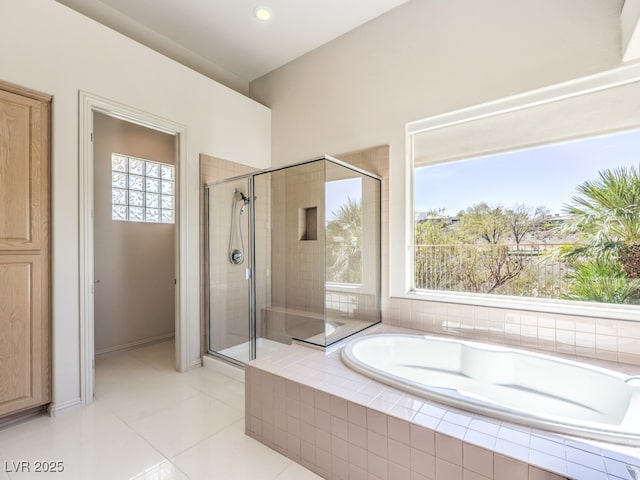 full bath featuring a stall shower, tile patterned flooring, a garden tub, and baseboards