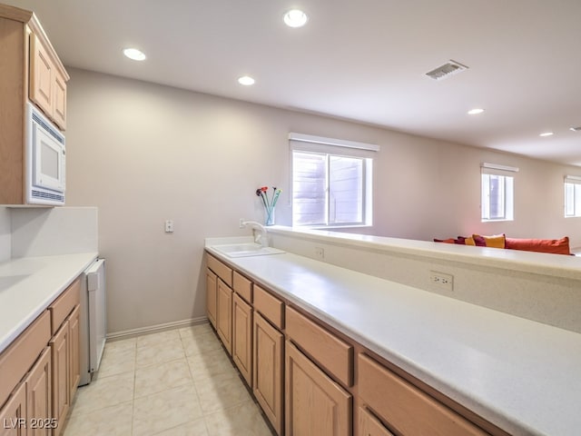 kitchen featuring recessed lighting, white microwave, visible vents, and a sink